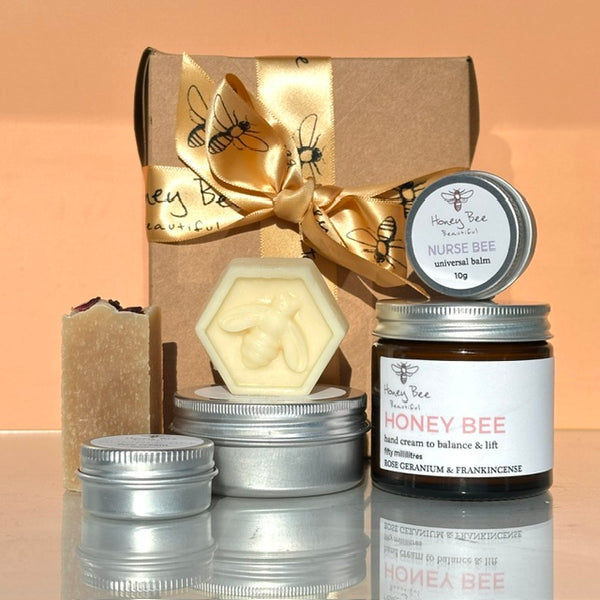 A honey bee themed gift set featuring a jar of honey bee hand cream, a hexagonal beeswax balm, a mini Nurse Bee balm, a mini iconic face cream and a mini rose,orange & patchouli honey soap in a gift box with a gold satin ribbon.
