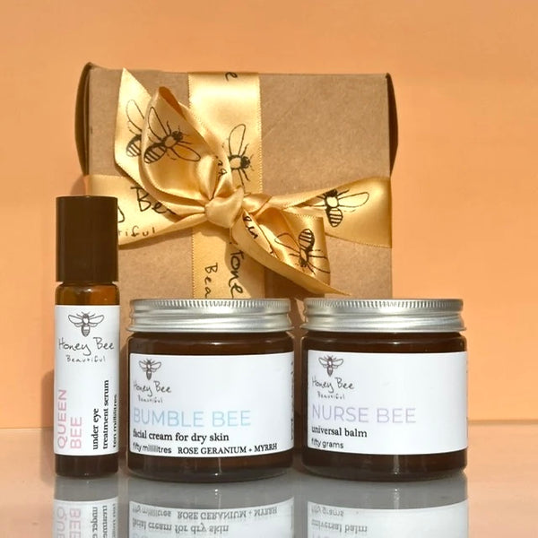 Three Honey Bee Beauty best selling skincare products in a eco card box with  gold satin ribbon: our most love Queen Bee Under Eye Oil, our iconic Bumble Bee Face Cream for dry skin, and our multi award winning Nurse Bee Universal Balm.